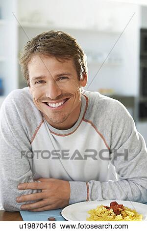 Stock Photo - Man sitting at table with plate of pasta. Fotosearch