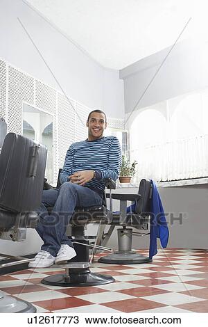Stock Image - Man sitting in barbers shop portrait. Fotosearch
