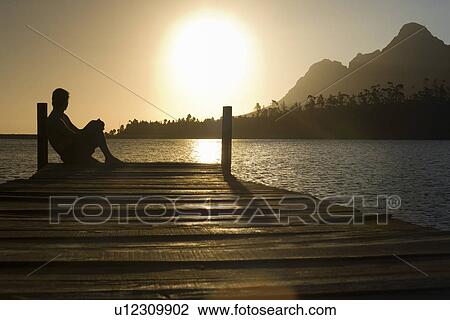 Man sitting on dock by lake side view. View Large Photo Image Stock Image - Man sitting on dock by lake side view.. Fotosearch