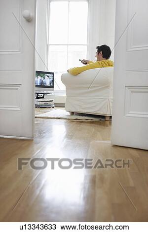 Man sitting on sofa watching television View Large Photo Image Stock Image - Man sitting on sofa watching television. Fotosearch