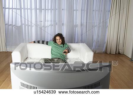 Man sitting on sofa watching television View Large Photo Image Stock Photo - Man sitting on sofa watching television. Fotosearch