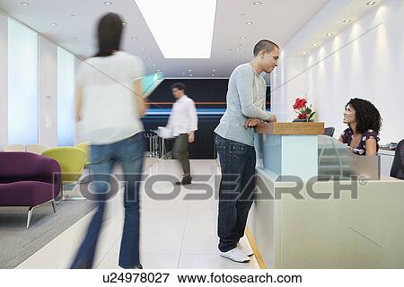 Man standing at reception desk Talking to Receptionist side view View Large Photo Image Stock Photo - Man standing at reception desk Talking to Receptionist side view. Fotosearch