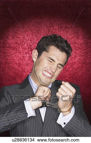 Man straining in handcuffs against red velvet background View Large Photo Image Picture - Man straining in handcuffs against red velvet background. Fotosearch