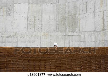 Man using cell phone behind stack of rebar on building site View Large Photo Image Stock Photo - Man using cell phone behind stack of rebar on building site. Fotosearch