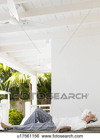 Man wearing headphones lying down on verandah View Large Photo Image Stock Photograph - Man wearing headphones lying down on verandah. Fotosearch
