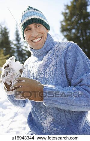 Picture - Man wearing winter clothing holding snowball portrait. Fotosearch