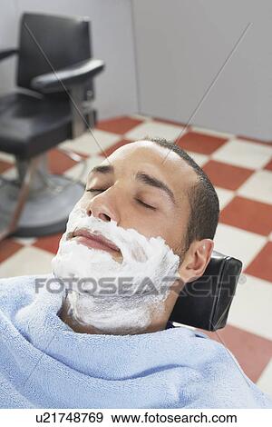Stock Photo - Man with shaving foam on face at barbers. Fotosearch