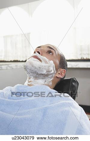 Stock Photo - Man with shaving foam on face at barbers. Fotosearch