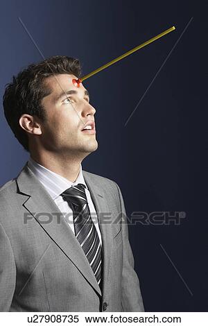 Stock Photography - Man with toy arrow in forehead against dark background. Fotosearch