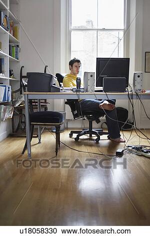 Stock Image - Man working on computer at home. Fotosearch