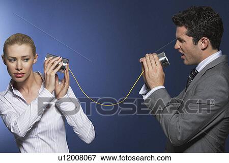 Stock Photo - Man yelling at woman through tin can phone against dark background. Fotosearch