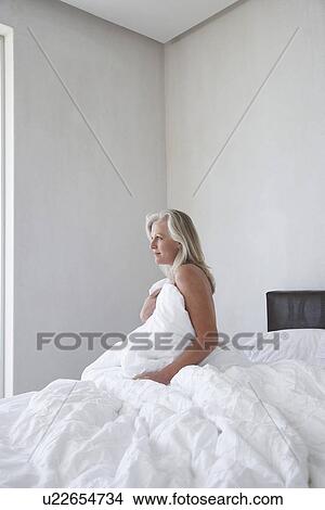 Mature woman in bathrobe sitting up in bed holding covers over chest side view View Large Photo Image Picture - Mature woman in bathrobe sitting up in bed holding covers over chest side view. Fotosearch