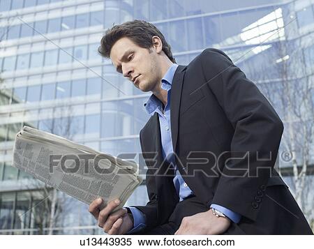 Mid-adult businessman reading newspaper in front of office building View Large Photo Image Stock Photography - Mid-adult businessman reading newspaper in front of office building. Fotosearch