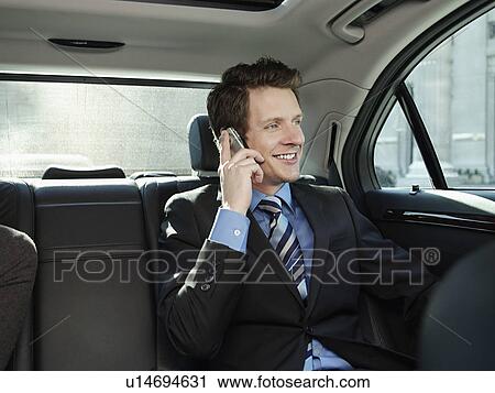 Mid adult businessman sitting at back seat of car using mobile phone View Large Photo Image Stock Image - Mid adult businessman sitting at back seat of car using mobile phone. Fotosearch