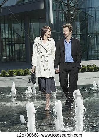 Mid-adult couple walking between water jets of fountain View Large Photo Image Stock Photo - Mid-adult couple walking between water jets of fountain. Fotosearch