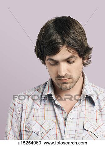 Stock Image - Mid adult man looking down. Fotosearch