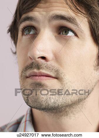 Stock Photo - Mid adult man looking up close-up of face. Fotosearch