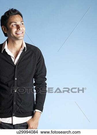 Picture - Mid adult man on blue background looking up and smiling. Fotosearch