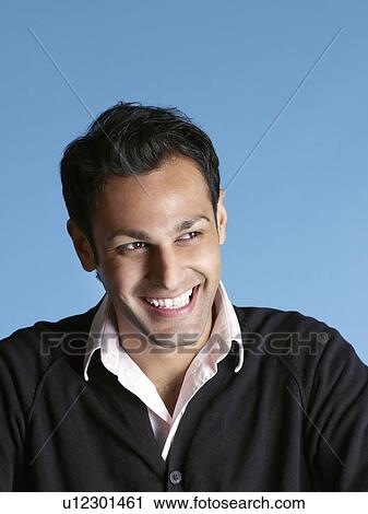 Stock Image - Mid-adult man on blue background looking away and laughing. Fotosearch