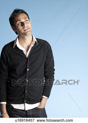 Stock Photo - Mid adult man on blue background looking to side and smiling. Fotosearch