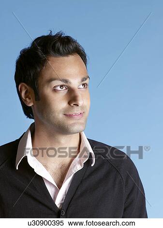Stock Photography - Mid adult man on blue background looking up and smiling. Fotosearch