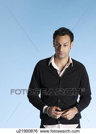 Stock Photograph - Mid adult man on blue background waist up. Fotosearch