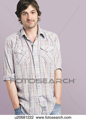 Stock Image - Mid adult man standing with hands in pockets. Fotosearch