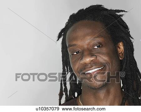 Stock Photo - Mid adult man with dreadlocks looking away close-up. Fotosearch