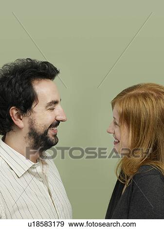 Stock Photo - Mid adult woman and man looking in eyes profile. Fotosearch