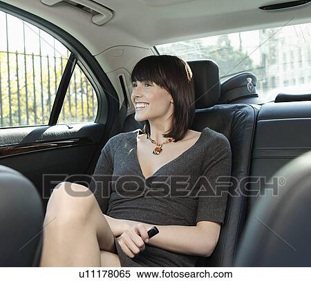 Stock Photography - Mid adult woman at back seat of car looking out window. Fotosearch