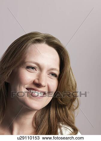 Mid-adult woman looking away and smiling close-up View Large Photo Image Stock Image - Mid-adult woman looking away and smiling close-up. Fotosearch