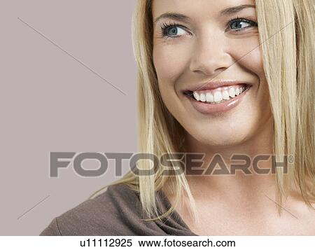 Stock Photography - Mid adult woman looking away and smiling close-up. Fotosearch