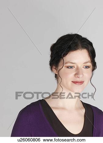 Stock Photograph - Mid adult woman looking down and smiling. Fotosearch