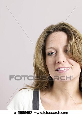 Stock Image - Mid-adult woman looking to side. Fotosearch
