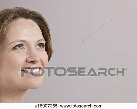 Stock Photography - Mid-adult woman looking up and smiling close-up. Fotosearch