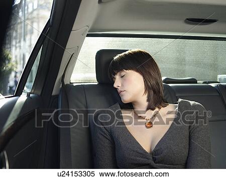 Stock Photography - Mid adult woman sleeping at back seat of car. Fotosearch