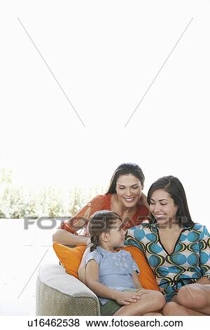 Mid-adult woman teenage girl (16-18) and girl (5-6) relaxing on sofa View Large Photo Image Stock Photo - Mid-adult woman teenage girl (16-18) and girl (5-6) relaxing on sofa. Fotosearch