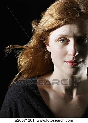 Stock Image - Mid adult woman with windswept hair close-up. Fotosearch