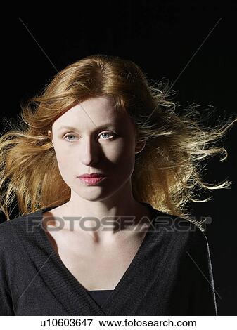 Stock Photo - Mid adult woman with windswept hair looking away close-up. Fotosearch