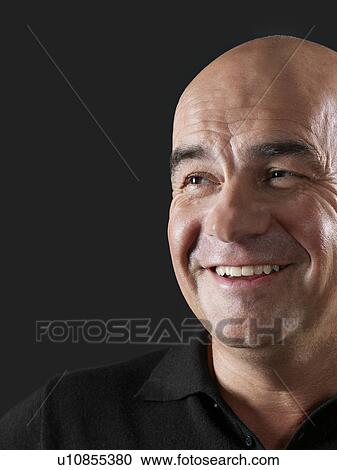 Stock Image - Middle-aged bald man looking away and smiling close-up. Fotosearch