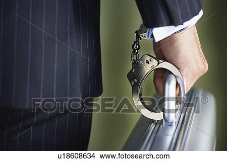 Middle-aged businessman handcuffed to briefcase mid section close-up back view View Large Photo Image Picture - Middle-aged businessman handcuffed to briefcase mid section close-up back view. Fotosearch