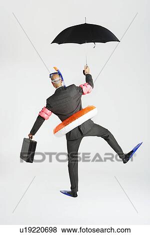 Middle-aged businessman in flippers inflatable rubber ring snorkel and goggles waddling carrying briefcase and umbrella back view View Large Photo Image Stock Photo - Middle-aged businessman in flippers inflatable rubber ring snorkel and goggles waddling carrying briefcase and umbrella back view. Fotosearch