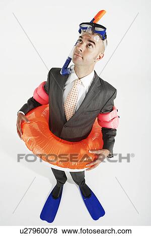 Stock Photo - Middle-aged businessman in flippers inflatable rubber ring snorkel and goggles looking up. Fotosearch