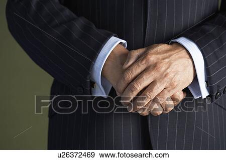 Stock Photo - Middle-aged businessman in full suit hands clasped mid section close-up. Fotosearch