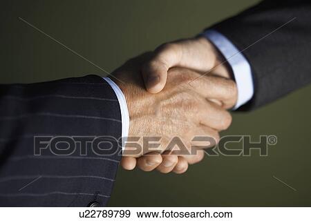 Stock Photo - Middle-aged businessmen shaking hands close-up. Fotosearch