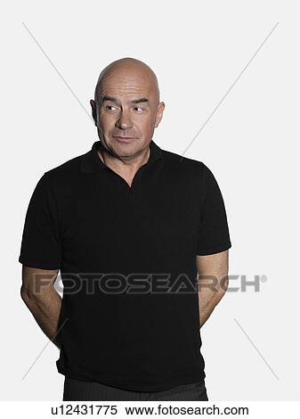 Middle-aged man standing with hands behind back and looking to side View Large Photo Image Stock Photography - Middle-aged man standing with hands behind back and looking to side. Fotosearch