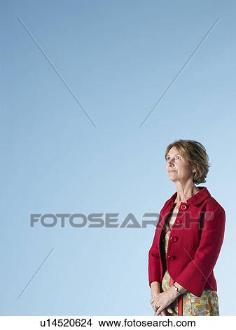 Middle-aged woman on blue background looking up View Large Photo Image Picture - Middle-aged woman on blue background looking up. Fotosearch