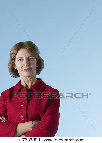 Stock Photo - Middle-aged woman on blue background arms crossed. Fotosearch