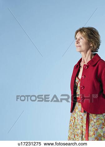 Stock Photography - Middle-aged woman on blue background looking up. Fotosearch