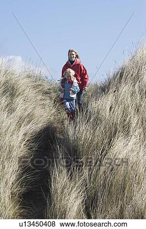 Mother and daughter (5-6) walking through long grass View Large Photo Image Stock Photo - Mother and daughter (5-6) walking through long grass. Fotosearch